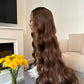 Side view of a brown wavy wig with a lace front, showcasing the natural waves and realistic texture