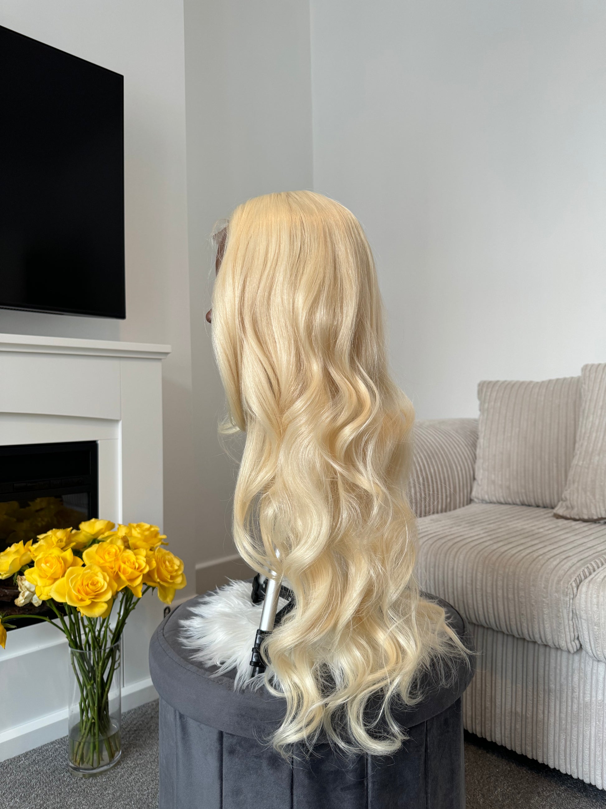 product Side view of a curly blonde wig with a lace front, showcasing the bouncy curls and natural-looking finish