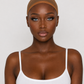 A woman wearing a sheer, skin-toned silicone or latex cap against a plain light gray background.