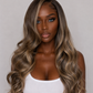 product A woman with long, wavy, highlighted hair wearing a white tank top, photographed against a plain light gray background.