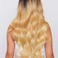 Long wavy ombre hair extension shown on a model from the back, featuring a dark brown root color that fades into a golden blonde.