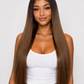 product A woman with very long, straight, dark brown hair with subtle lighter brown highlights, wearing a white tank top and blue jeans, photographed against a light gray studio background. product
