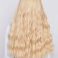 Close-up of a synthetic blonde wig with soft waves and trendy bangs, ideal for a chic and modern appearance