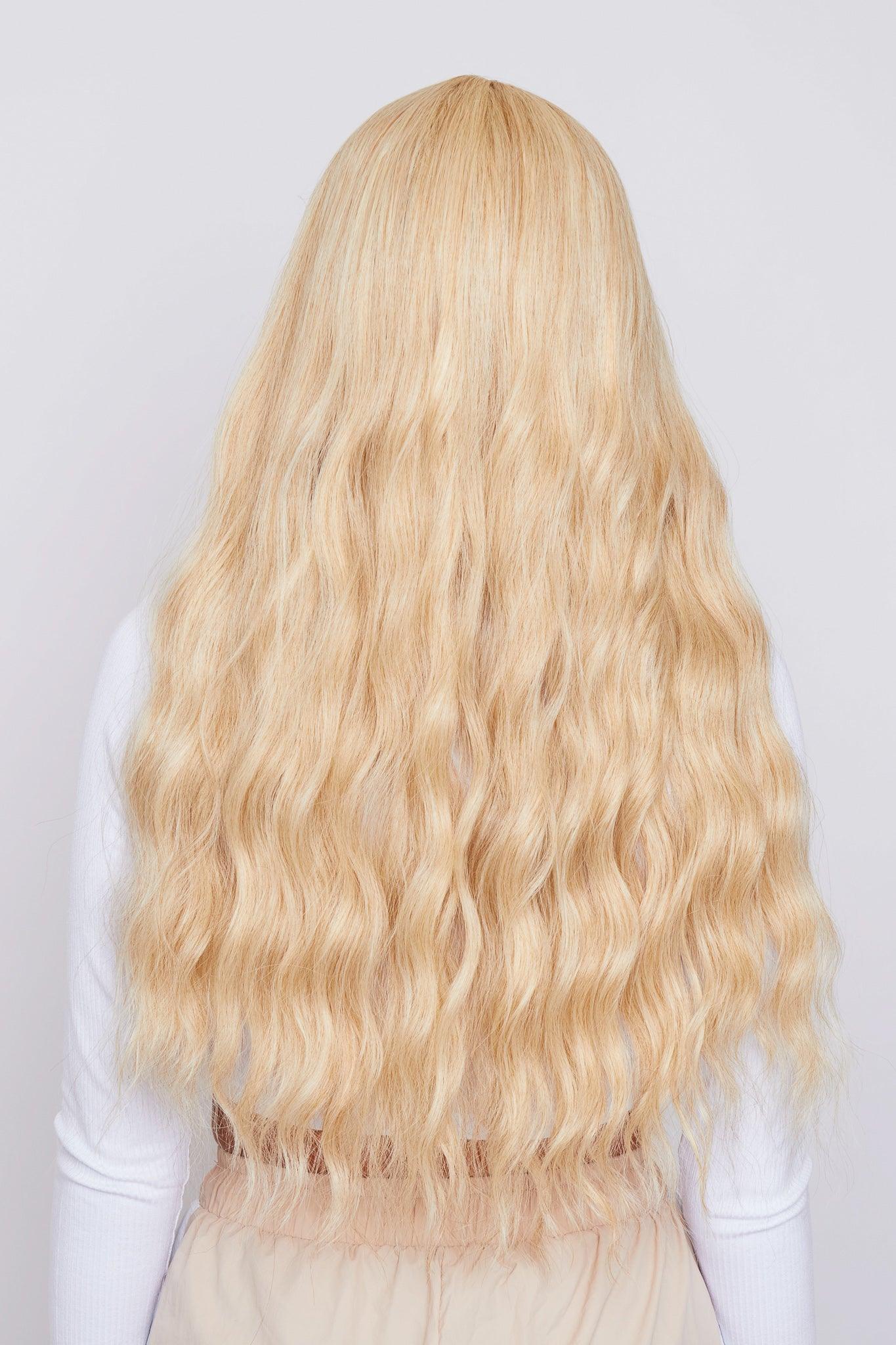 Close-up of a synthetic blonde wig with soft waves and trendy bangs, ideal for a chic and modern appearance
