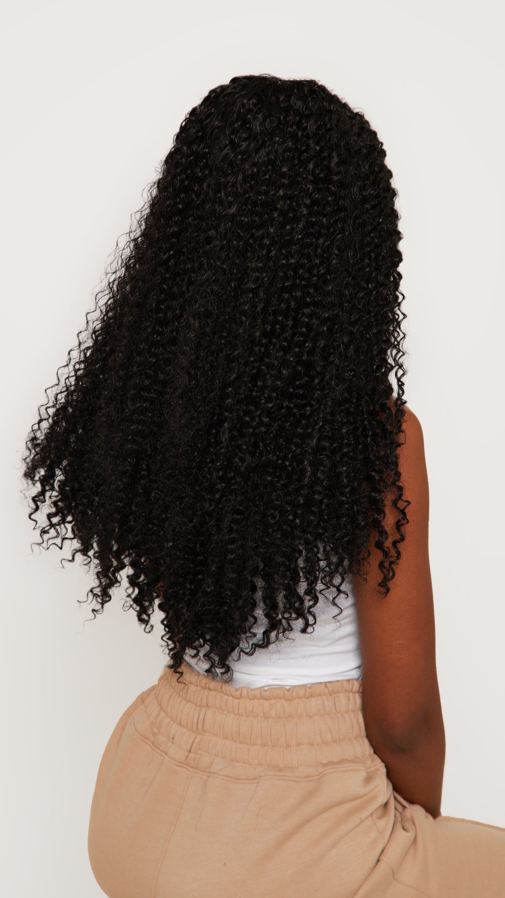 Back view of a kinky curly black wig, emphasizing the voluminous curls and seamless synthetic fibers